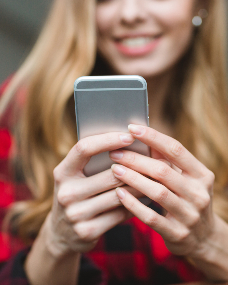 Woman using a smartphone to check her online digital home inspection report by Carolina HomePro Inspections